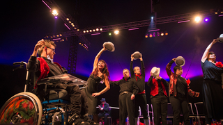 Eine Theatergruppe tanzt im Scheinwerferlicht