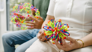 Hände halten einen bunten Ball